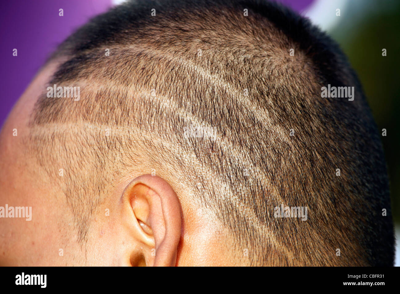 Testa di uomo con linee di chiudere tagliate i capelli rasata acconciatura a Patong, Phuket, Tailandia Foto Stock
