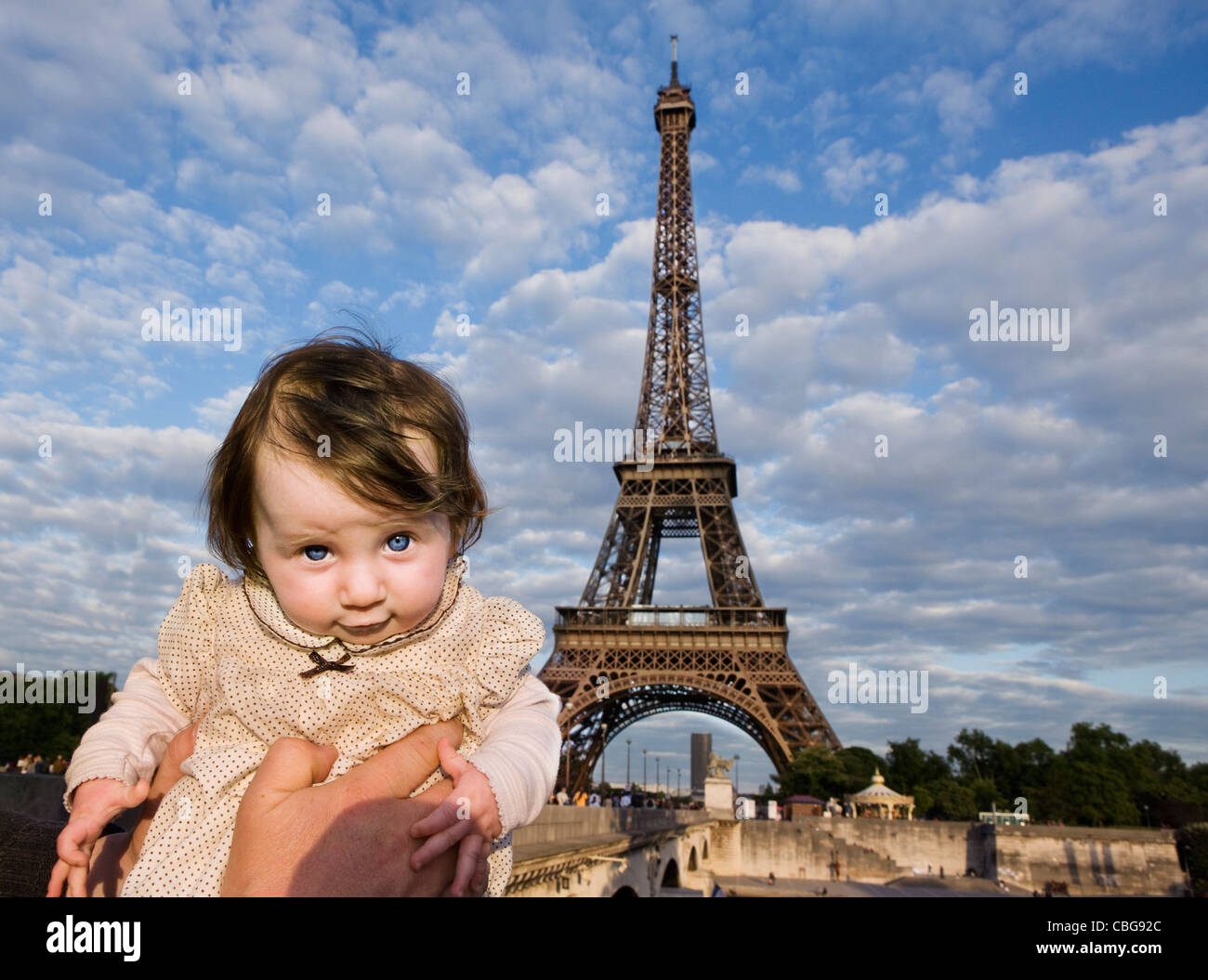 Un bambino essendo mantenuto aloft davanti alla Torre Eiffel, Parigi, Francia Foto Stock