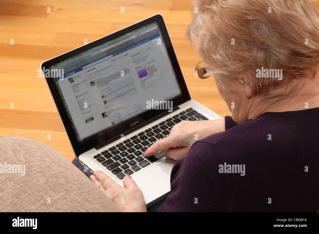 Donna matura usando il suo computer portatile, su internet con una rete sociale sullo schermo. Foto Stock