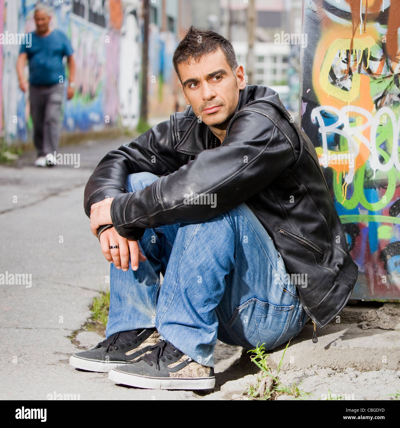 Adulto Uomo bello in posa all'aperto in un muro di graffiti sullo sfondo Foto Stock