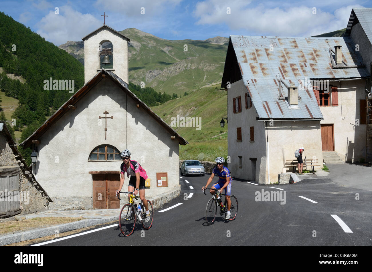 Ciclisti in bicicletta attraverso Boulieyas Hamlet, Saint Dalmas-le-Selvage, Valle Tinée, sulla Route de la Bonette, Alpi Marittime Francia Foto Stock