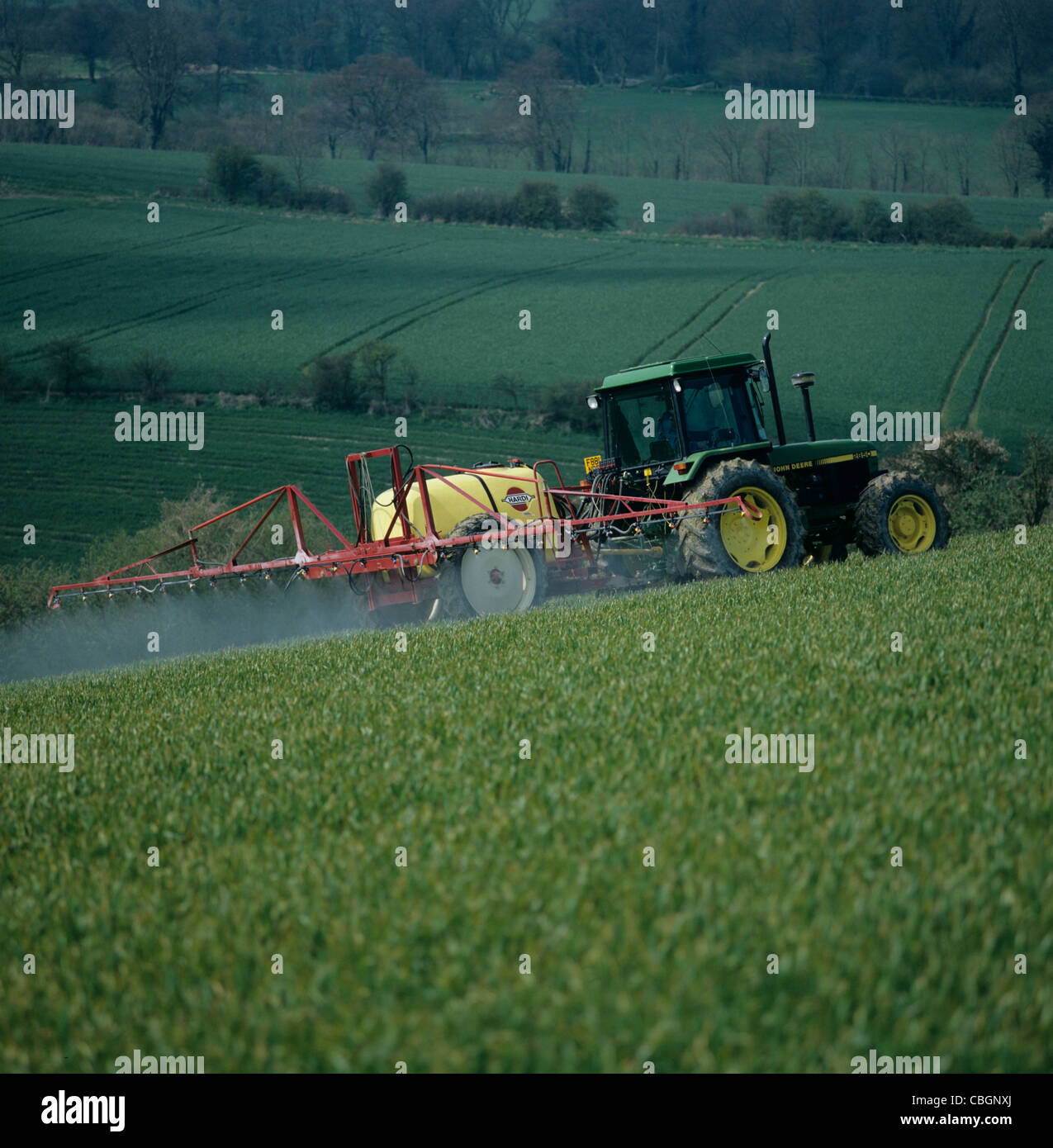 Trattore John Deere & Hardi irroratrice trainata la spruzzatura di coltivazione di grano in primavera Foto Stock