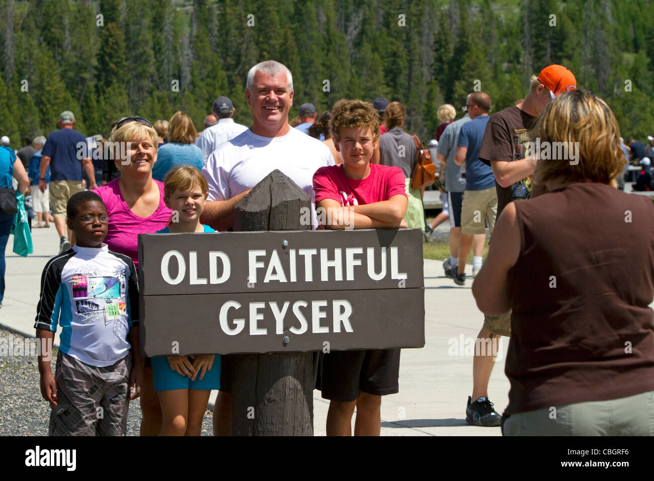 I turisti posano per una foto a geyser Old Faithful nel Parco Nazionale di Yellowstone, Wyoming negli Stati Uniti. Foto Stock