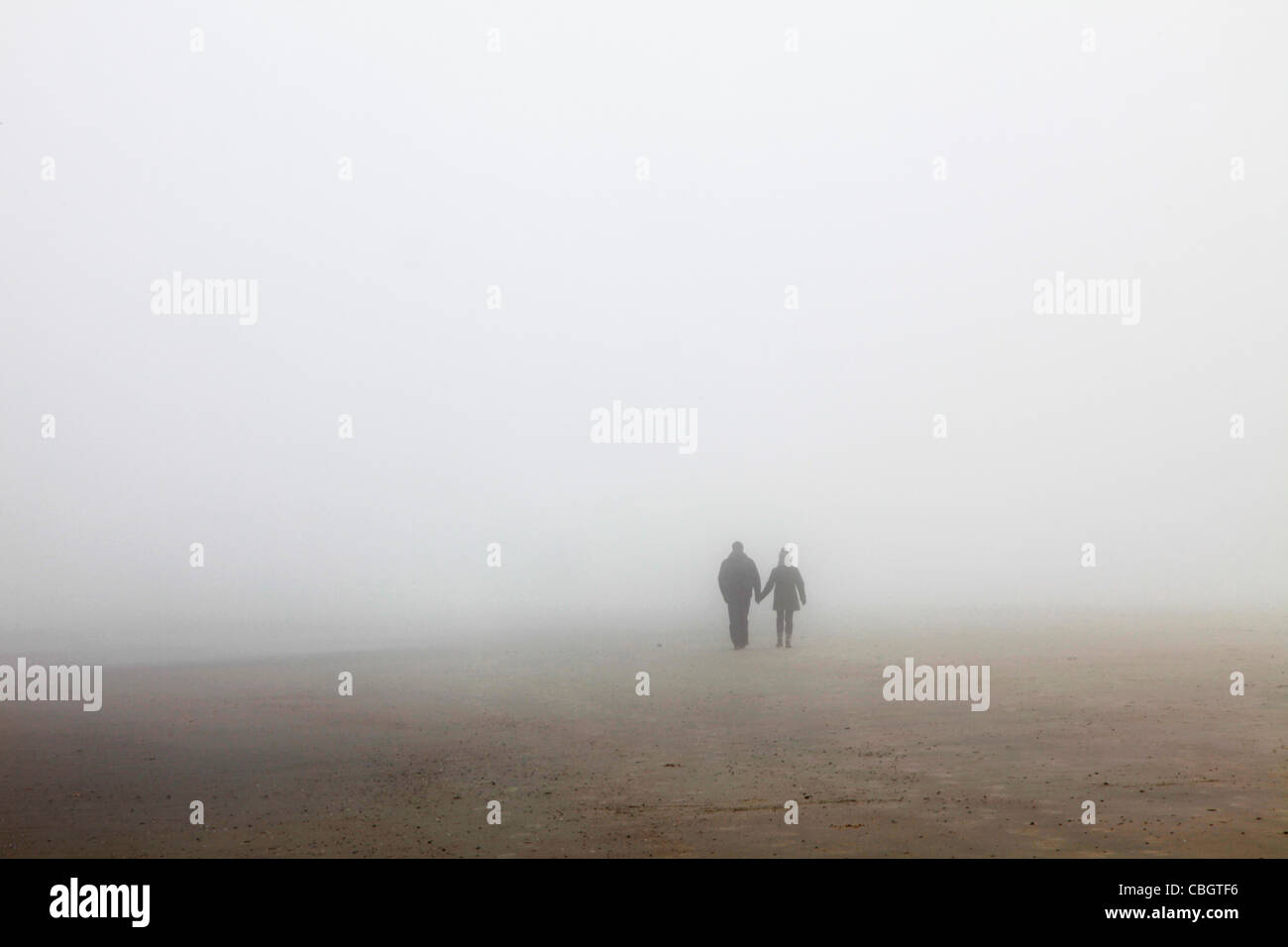 Un molto nebbioso giorno in spiaggia. La scarsa visibilità, 2 persone che camminano nella nebbia. Spiekeroog, Bassa Sassonia, Germania, Europa. Foto Stock