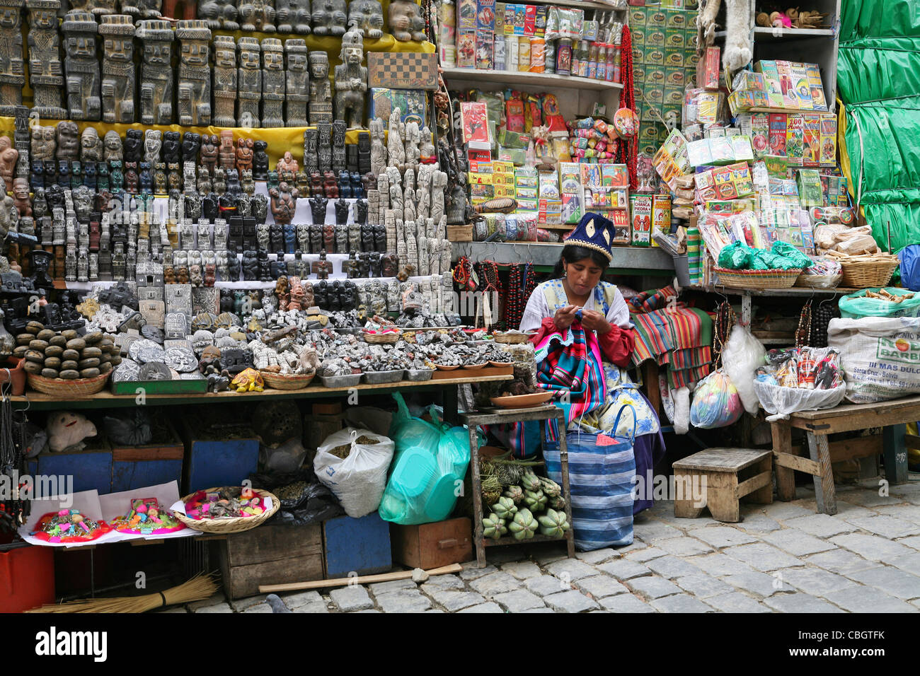 Nativo di donna boliviana maglia in stallo di mercato con negozio di souvenir per i turisti a la strega il mercato nella città di La Paz, Bolivia Foto Stock