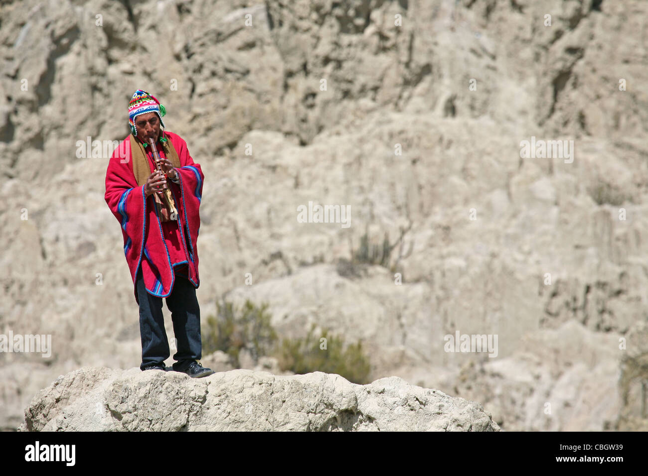 Vestito tradizionale indiano nativo flautista con il poncho nella Valle della Luna / Valle de la Luna vicino a La Paz in Bolivia Foto Stock