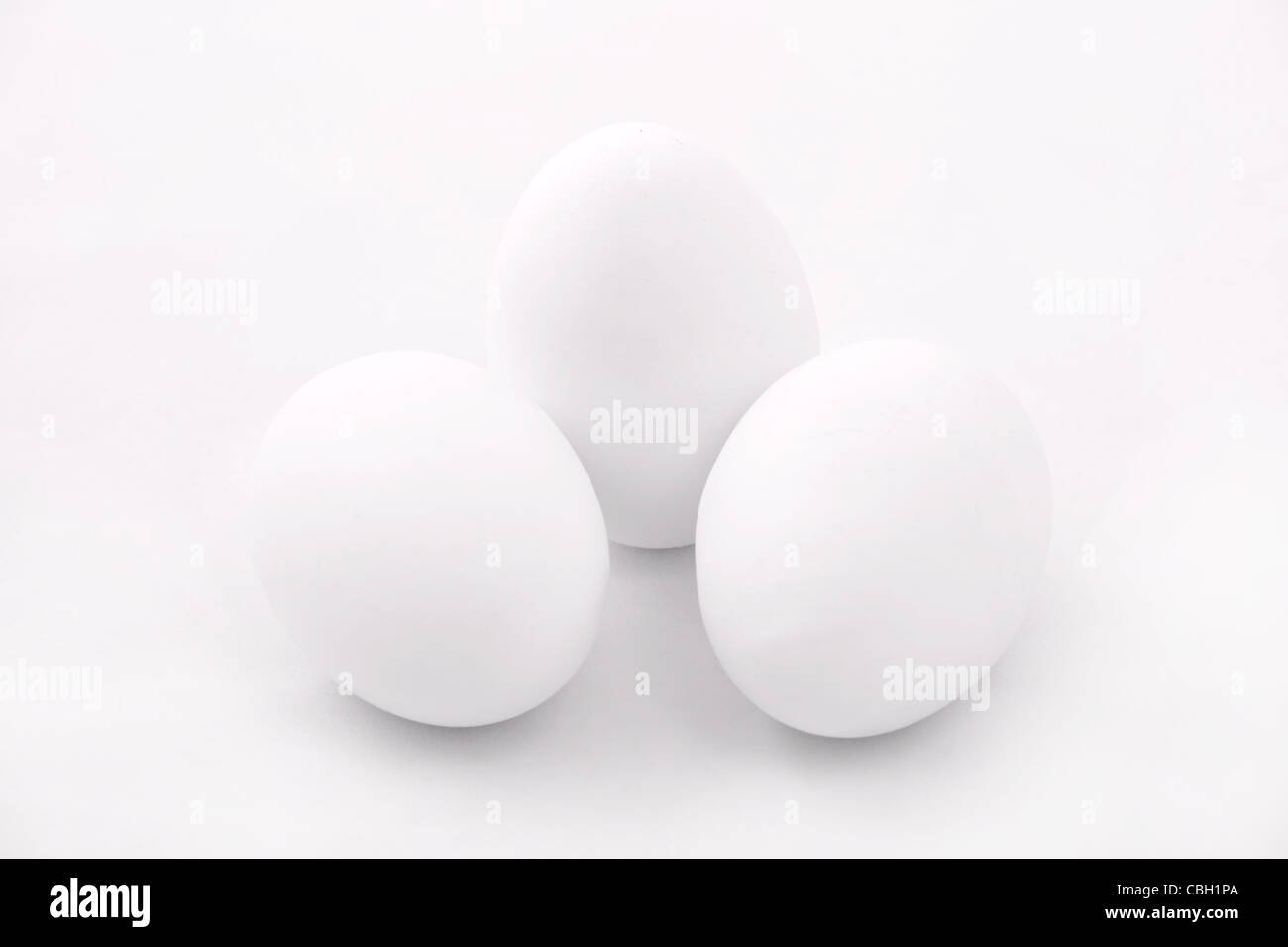 Tre uova sulla superficie bianca. Bianco su bianco serie. Studio shot. Foto Stock