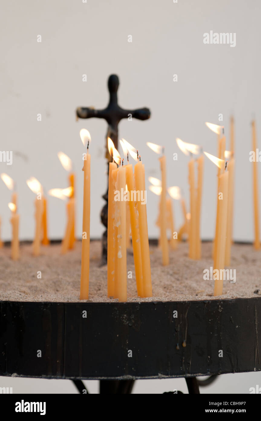 La masterizzazione di candele di cera nella chiesa ortodossa con una croce cristiana Foto Stock