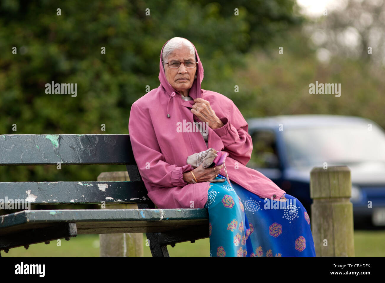 Un'anziana donna seduta su una panchina. Foto Stock