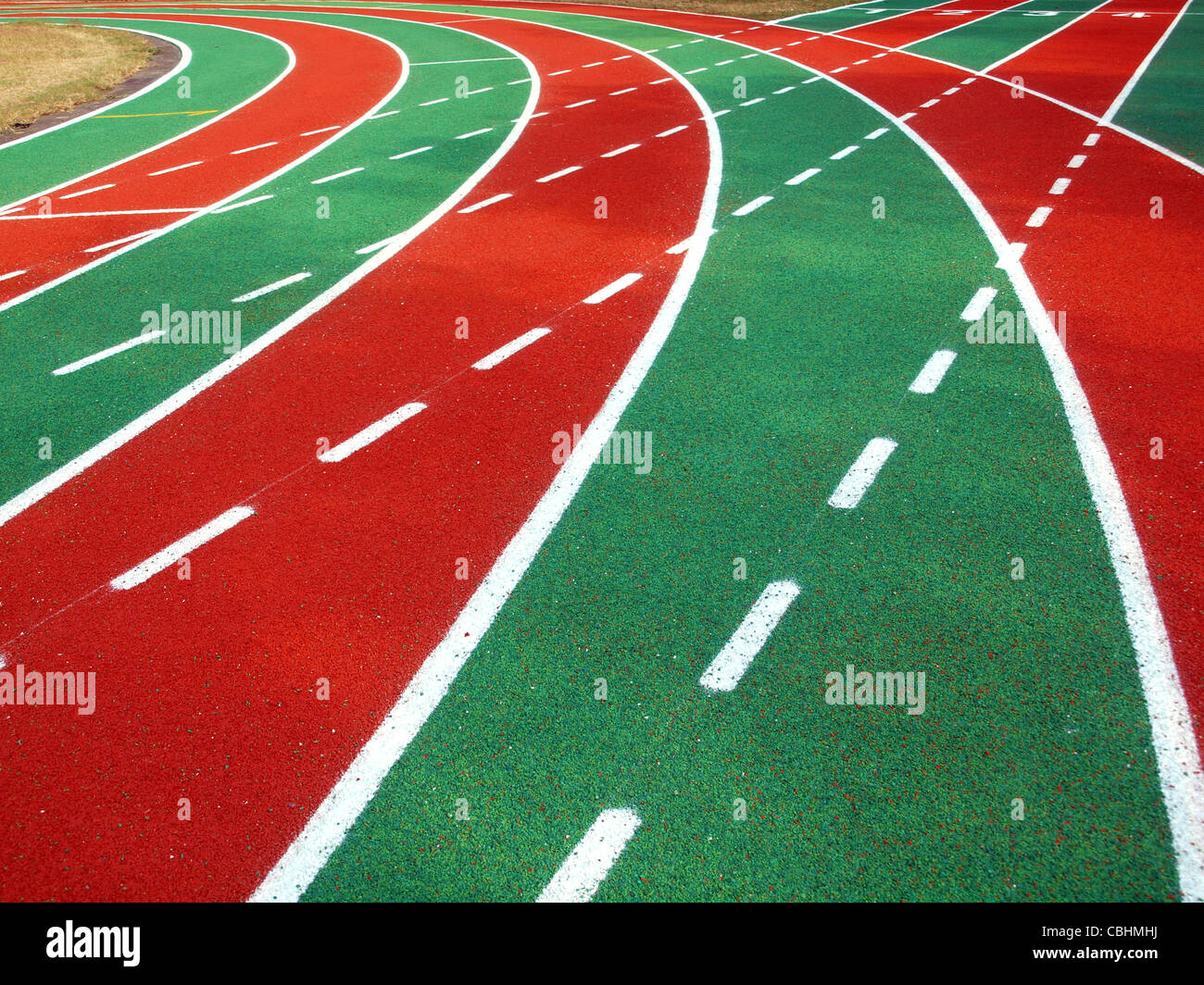 Corsa atletica via con il rosso e il verde della superficie in gomma bianca e marcature di corsia Foto Stock