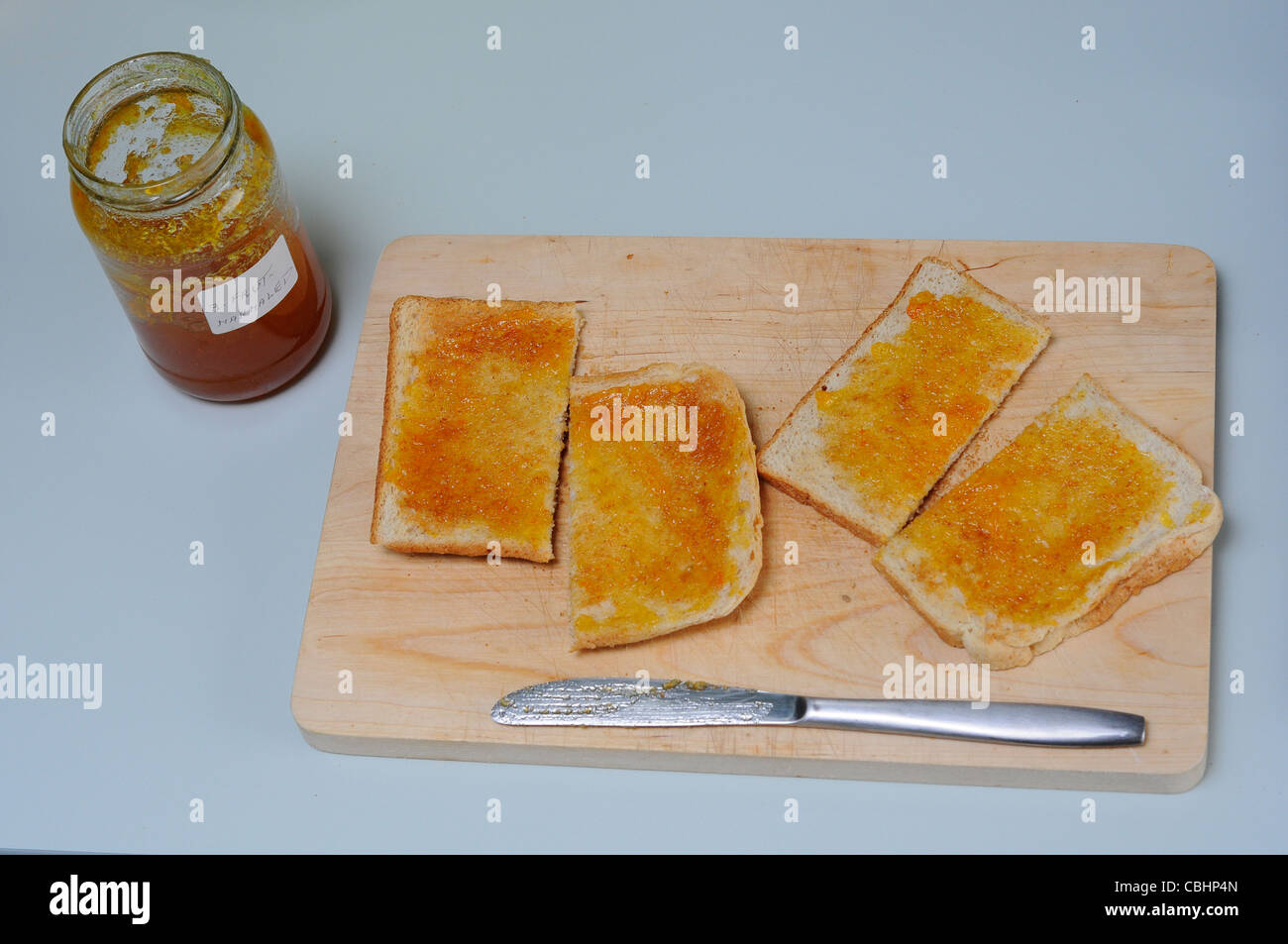 Facendo colazione a base di pane tostato con marmellata di arance Foto Stock