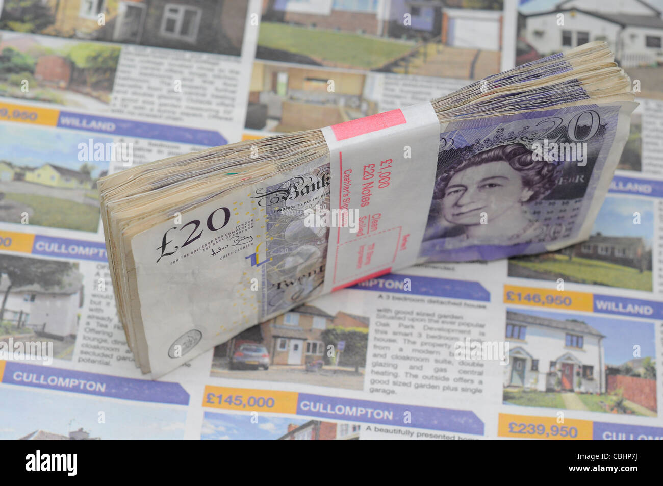 Il concetto di proprietà denaro sul giornale annunci case in vendita. £1000, mensile ipotecari pagamenti o di risparmio per i mutui ipotecari. Foto Stock