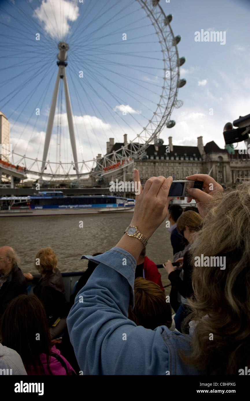 Donna su una Londra Tamigi tour guidato a fotografare il London Eye sulla banca del sud Foto Stock