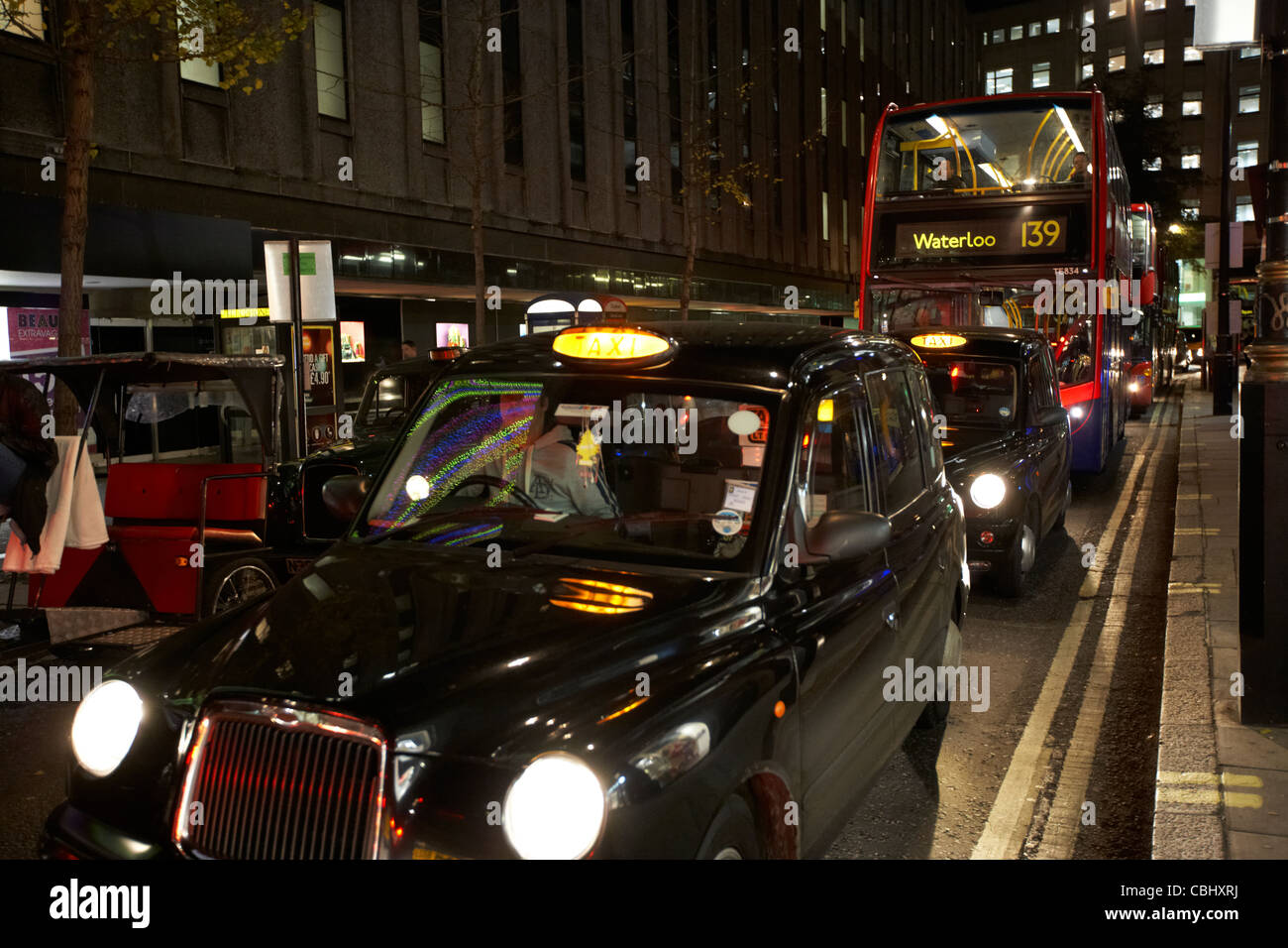Fila di black london taxi I taxi e bus di notte bloccati nel traffico su strada per lo shopping in centro a Londra England Regno Unito Regno Unito Foto Stock