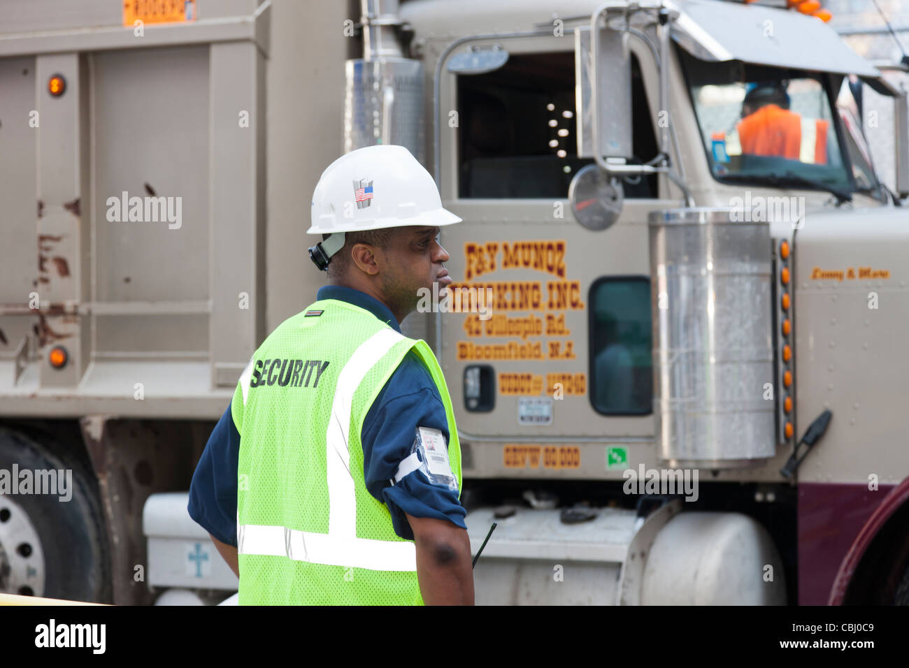 Una guardia di sicurezza orologi un autocarro con pianale di scarico che esce dal World Trade Center sito in costruzione nella città di New York. Foto Stock