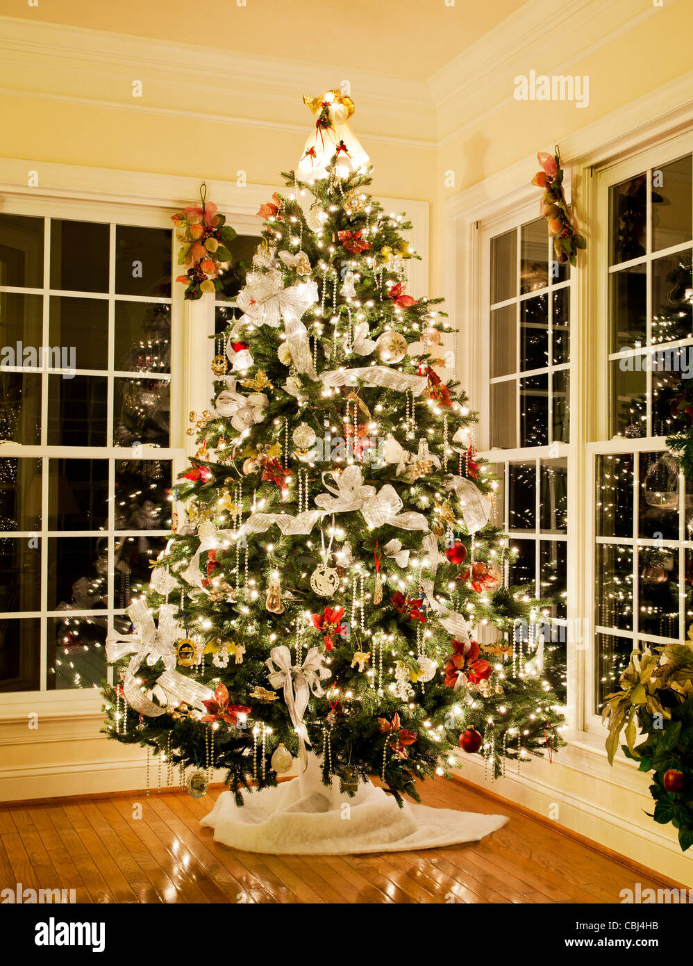 Albero di Natale decorato con argento e bianco nastri e ornamenti nella casa di famiglia Foto Stock