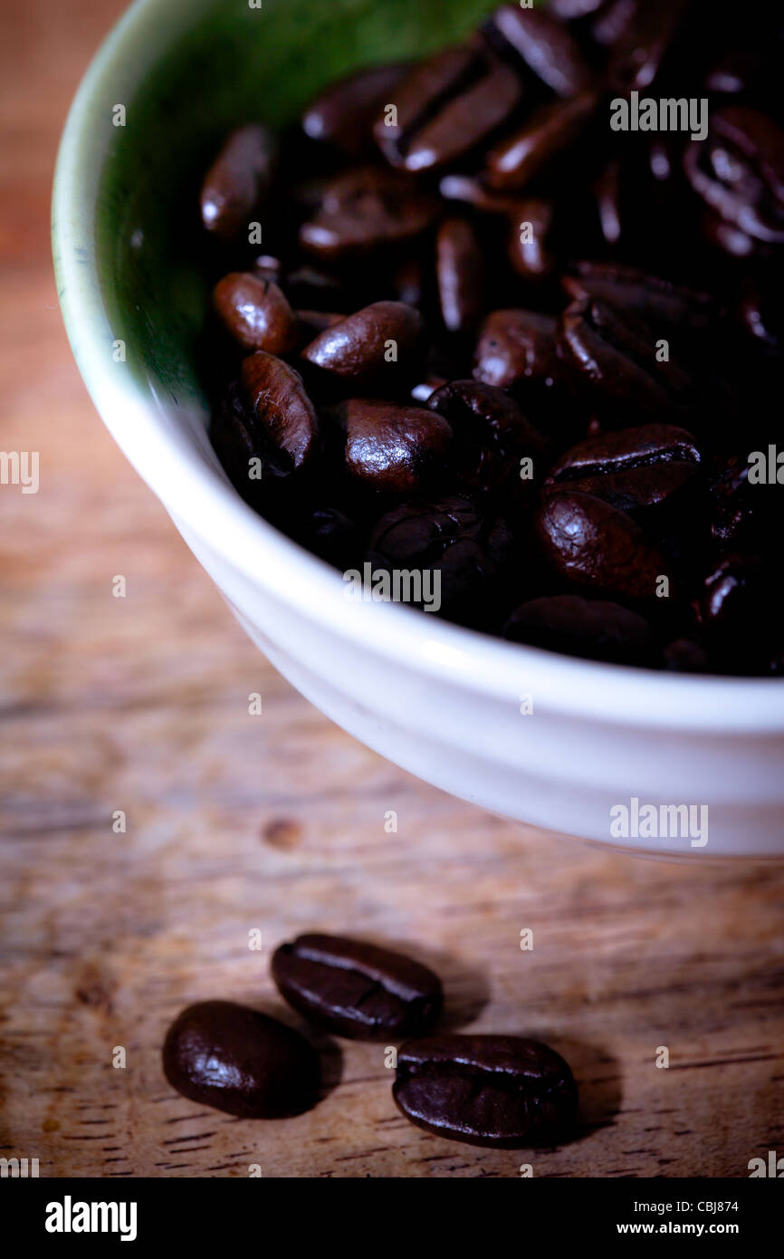 I chicchi di caffè in una ciotola bianco, Sfondo legno Foto Stock