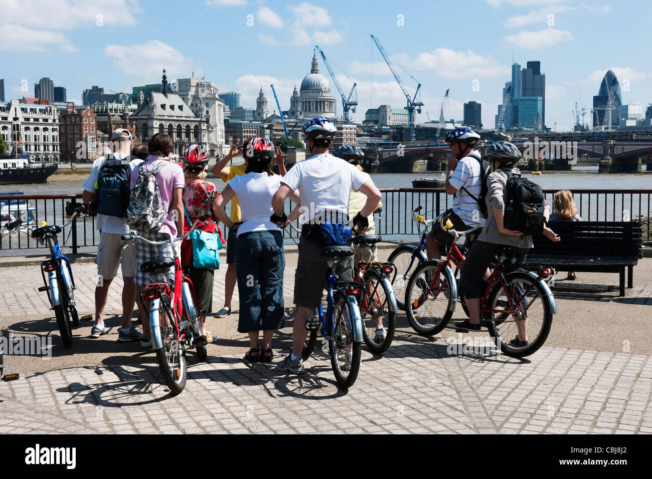 I ciclisti che indossa caschi di sicurezza ricevere istruzioni sulla South Bank di Londra con il London City skyline in background Foto Stock