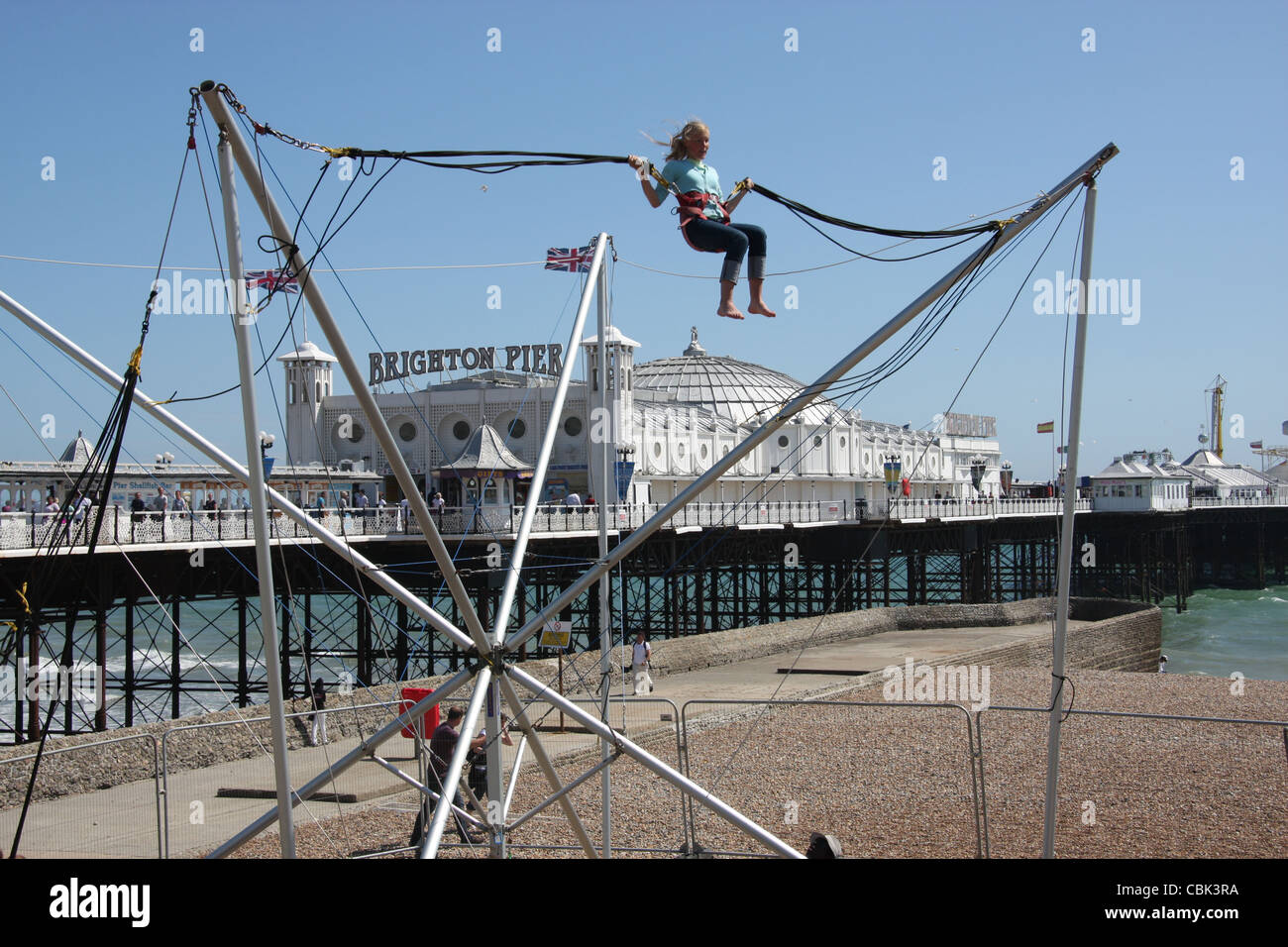 Un turista godendo di una corsa sulla spiaggia vicino al molo di Brighton Foto Stock