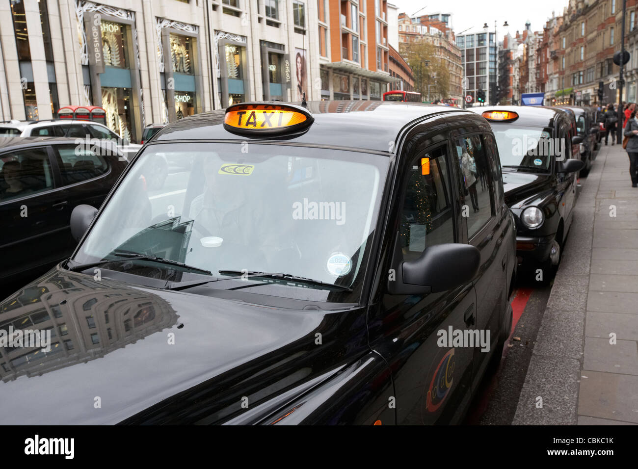 Fila di black london taxi I taxi a noleggio su knightsbridge shopping street nel centro di Londra England Regno Unito Regno Unito Foto Stock