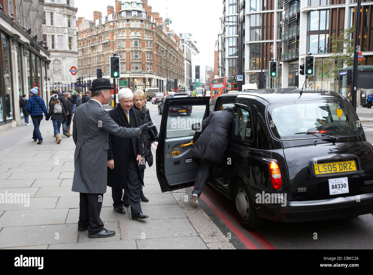 Portiere da Harvey Nichols apre la porta della cabina per i clienti in centro a Londra England Regno Unito Regno Unito Foto Stock