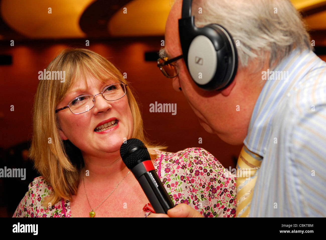 Femmina essendo delegato intervistato per live radio broadcast in occasione di una conferenza per la gente la cura per famiglie di dipendenti, Londra, Regno Unito. Foto Stock