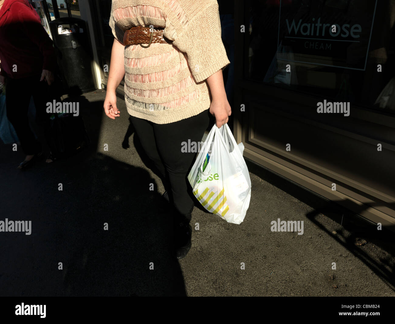 Donna venuta fuori del supermarket Waitrose che trasportano derrate alimentari in materiale plastico riciclabile Shopping Bag Cheam Village Inghilterra Foto Stock