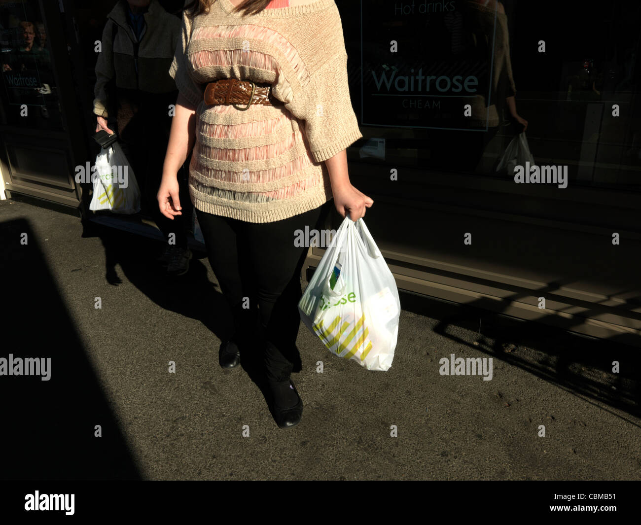 Le donne in uscita del supermarket Waitrose che trasportano derrate alimentari in materiale plastico riciclabile Shopping Bag Cheam Village Inghilterra Foto Stock