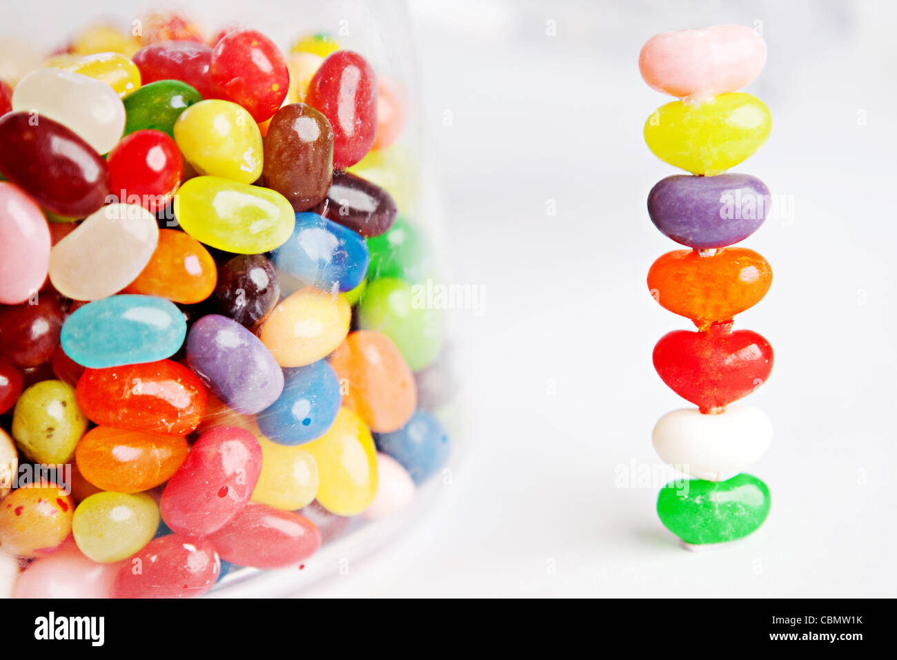 Una torre di coloratissimi jelly bean dolci posto accanto a un vaso di vetro di Jelly Beans Foto Stock