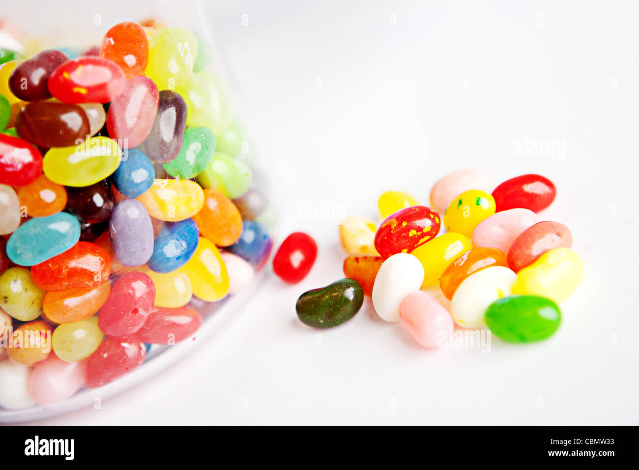 Una manciata di jelly bean dolci posto accanto a un vaso di vetro di Jelly Beans Foto Stock