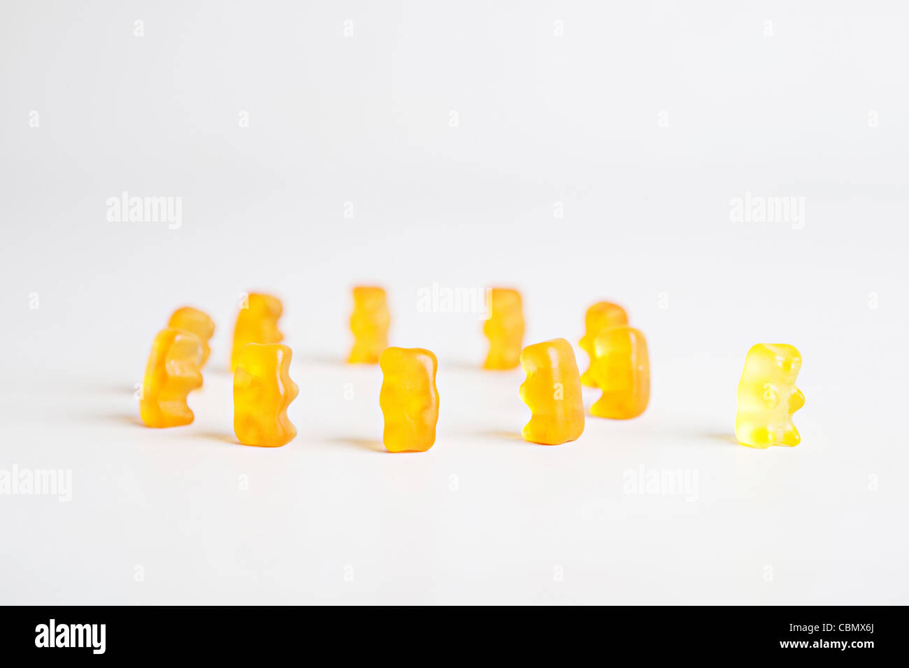 Un cerchio di colore arancione orsi gommoso con un orso giallo sul lato esterno a dare un messaggio concettuale su "intruso" Foto Stock