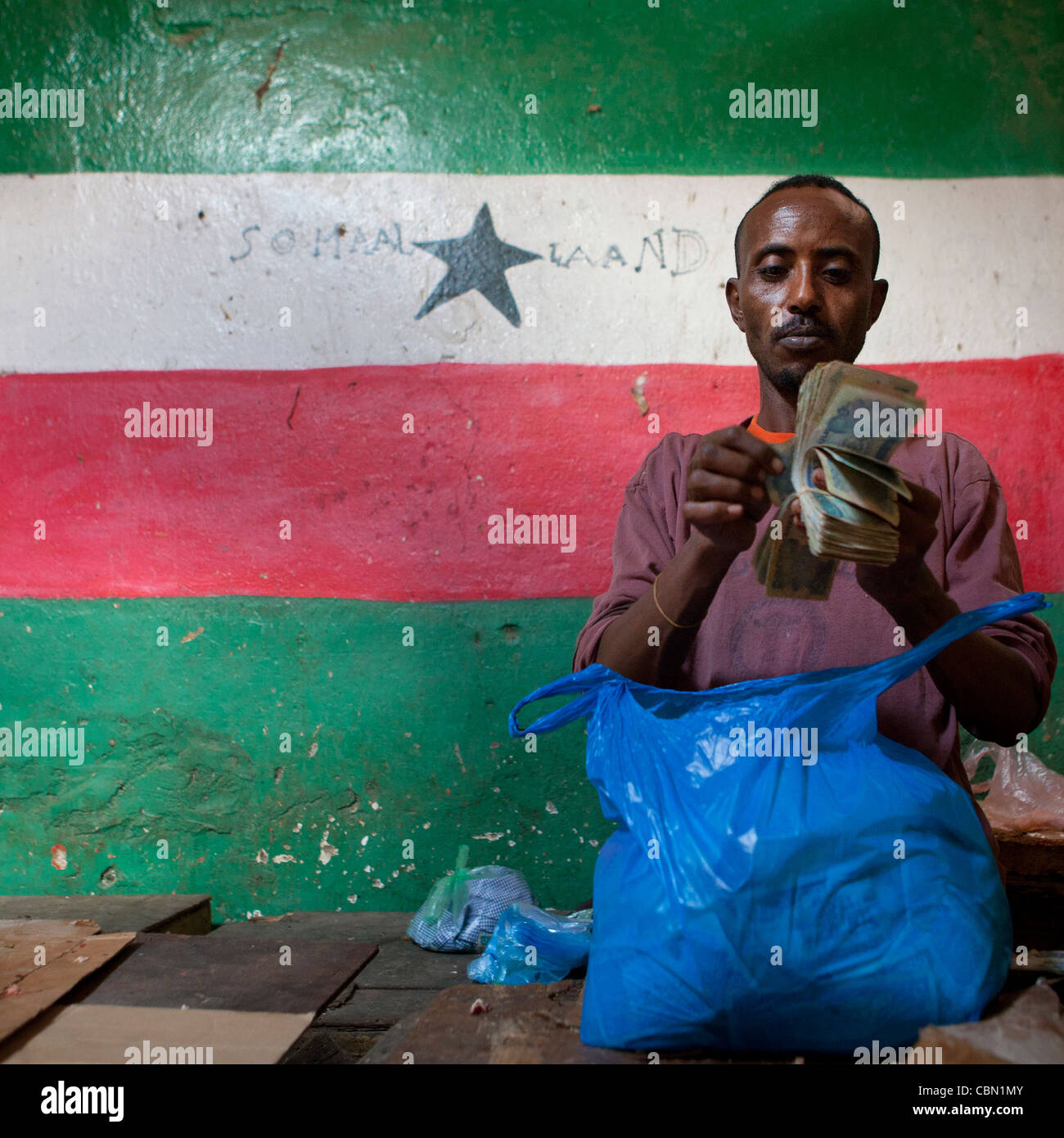 L'uomo contando le fatture nella parte anteriore del Somaliland bandiera Hargeisa Somaliland Foto Stock