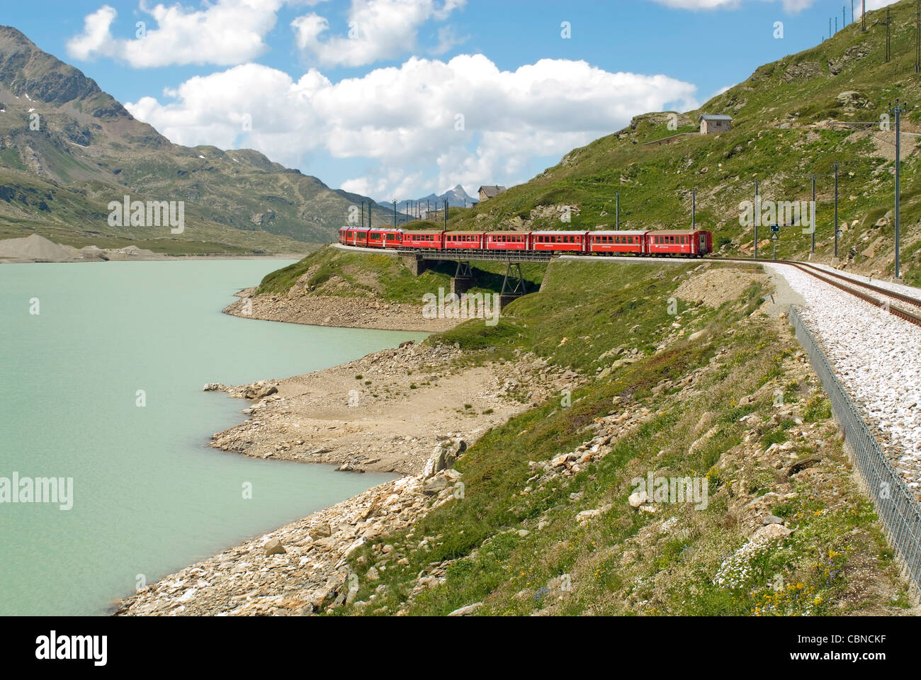 Treno alpino in un paesaggio montano al Lago Bianco, Passo Bernina, Grigioni, Svizzera in estate Foto Stock