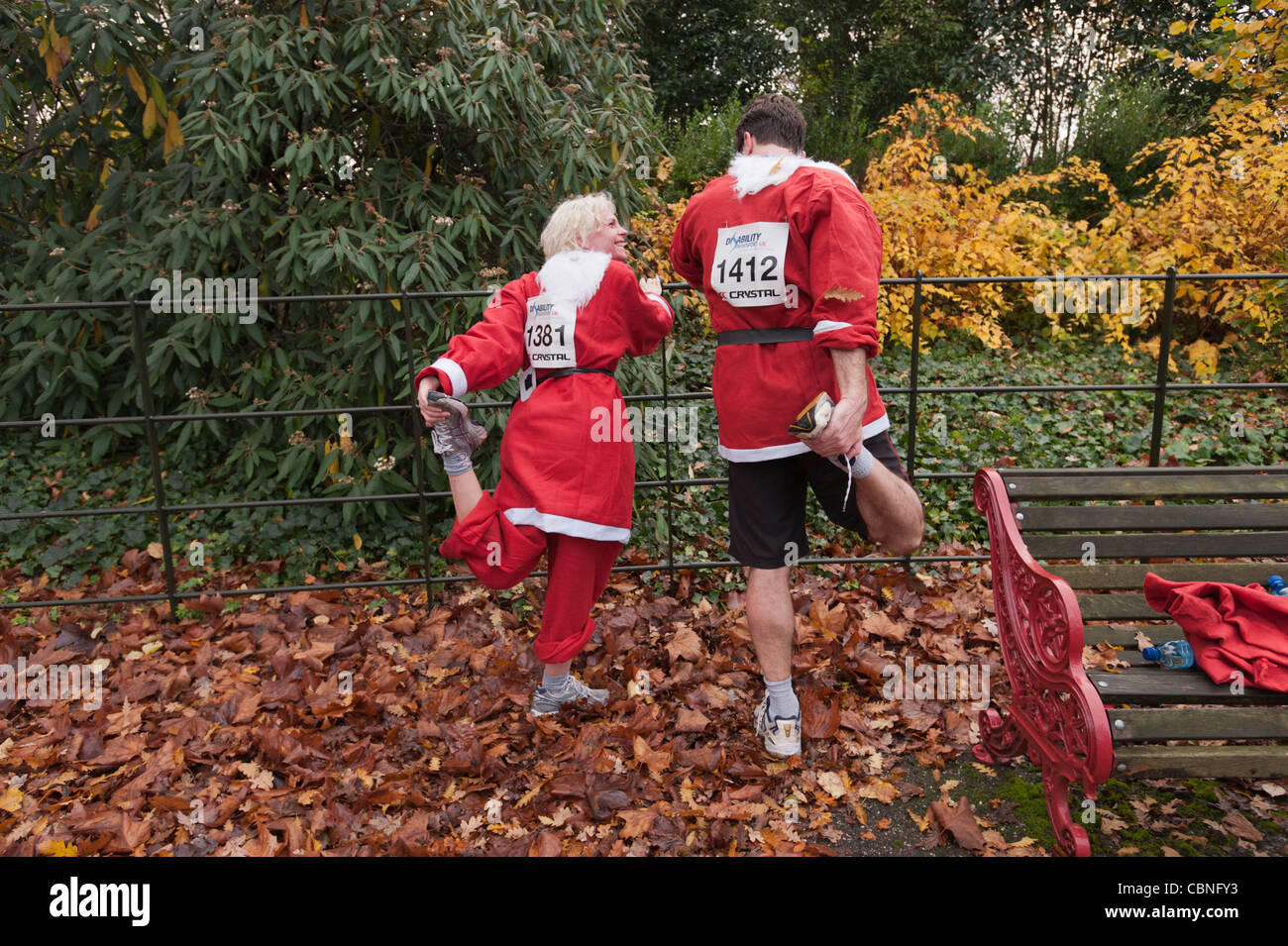 I corridori dopo l annuale Santa eseguire nella zona londinese di Battersea Park stretching dopo la finitura l annuale 10K della fun run Foto Stock