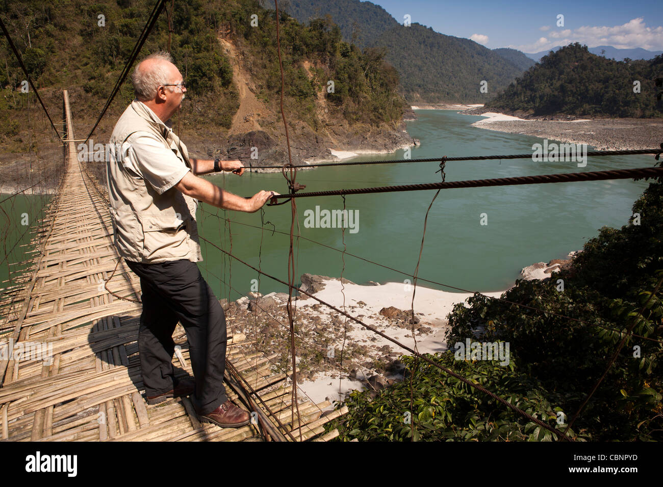 India, Arunachal Pradesh, Kabang, foothills dell'Himalaya, uomo occidentale attraversando la sospensione ponte sul fiume Siang Foto Stock