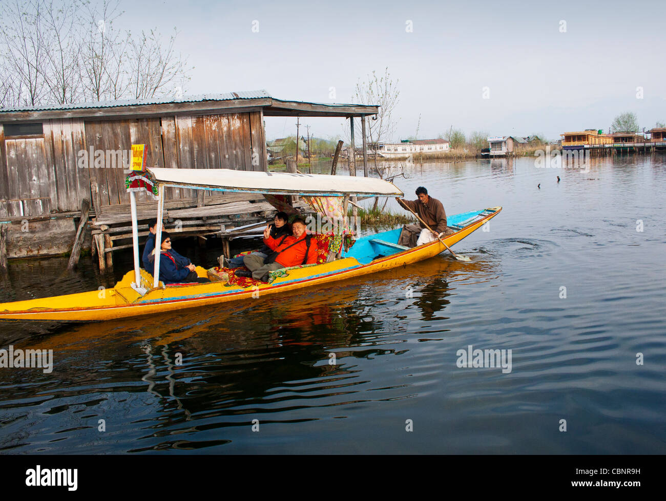I turisti si sposteranno per il lago dal a Srinagar che voga una tradizionale barca shikara/canoa/campagna, Kashmir, India Foto Stock