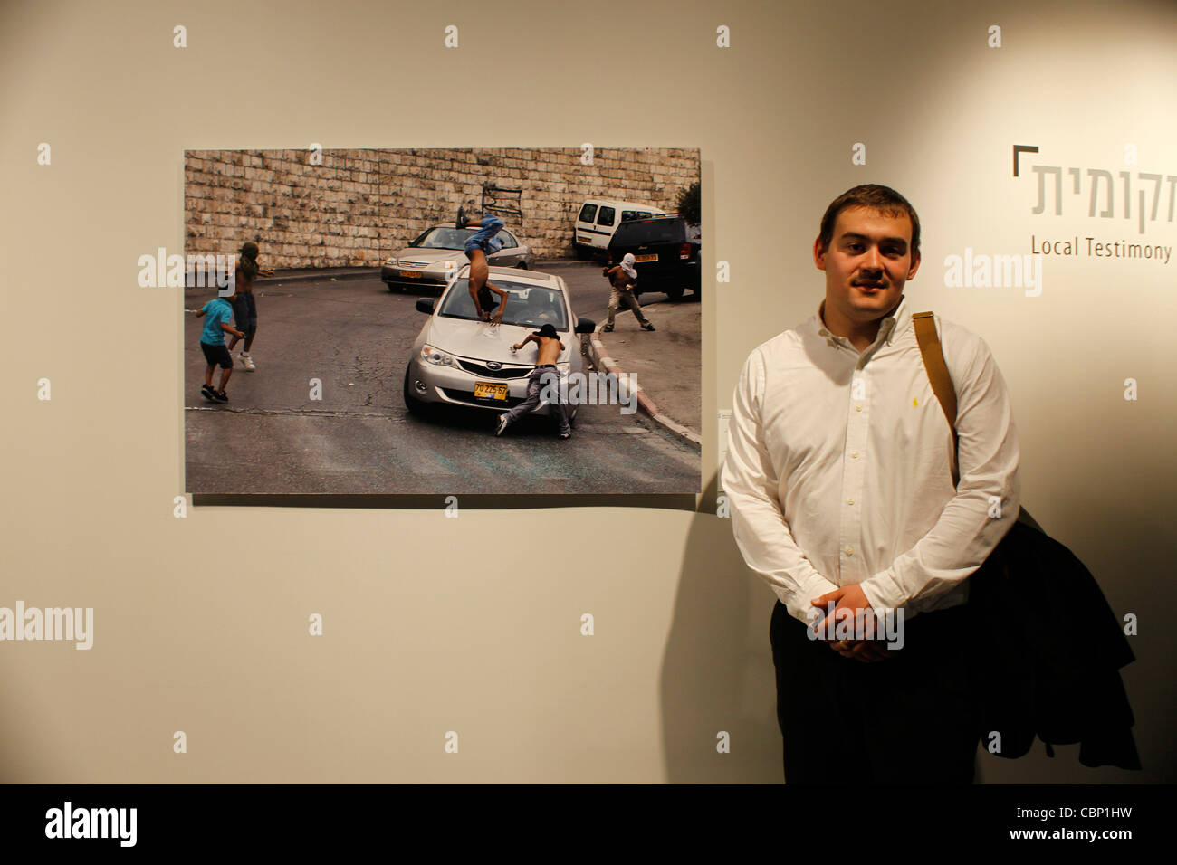 Fotoreporter israeliano Ilia Yefimovich sorge nella parte anteriore della sua fotografia vincente scelto come miglior foto dell'anno presso il locale "testimonianza" concorso di fotogiornalismo svolge in Eretz Israel Museum di Tel Aviv il 13 dicembre 2011. La foto mostra una vettura guidata dal presidente di una organizzazione dedicata a stimolare la presenza ebraica a Gerusalemme in esecuzione su bambini palestinesi che erano lanciare sassi a lui Foto Stock