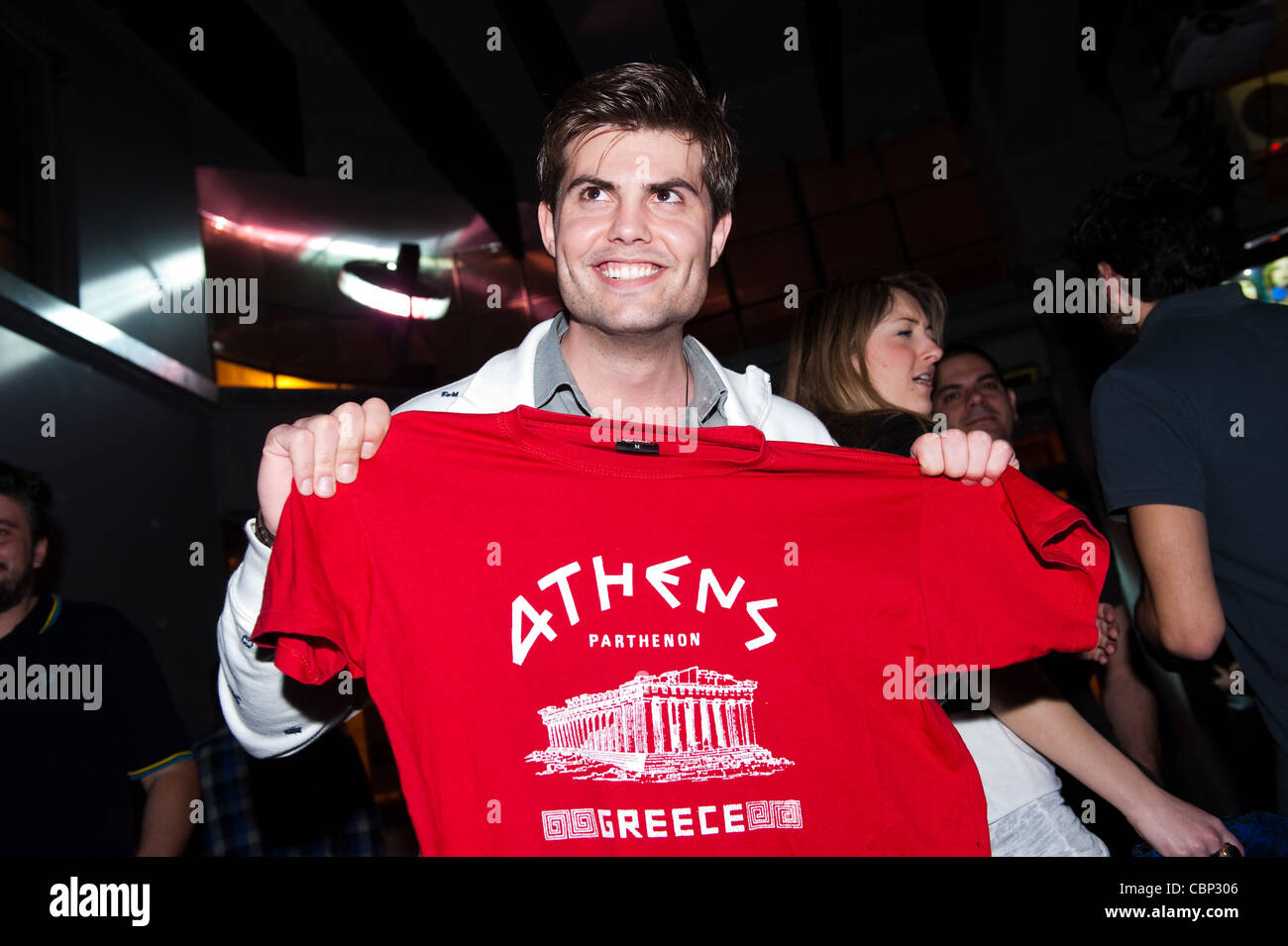 Athenian tenendo un kitsch t-shirt con il Partenone su una notte fuori nella barra del Bios nella Gazi area di Atene. Foto Stock