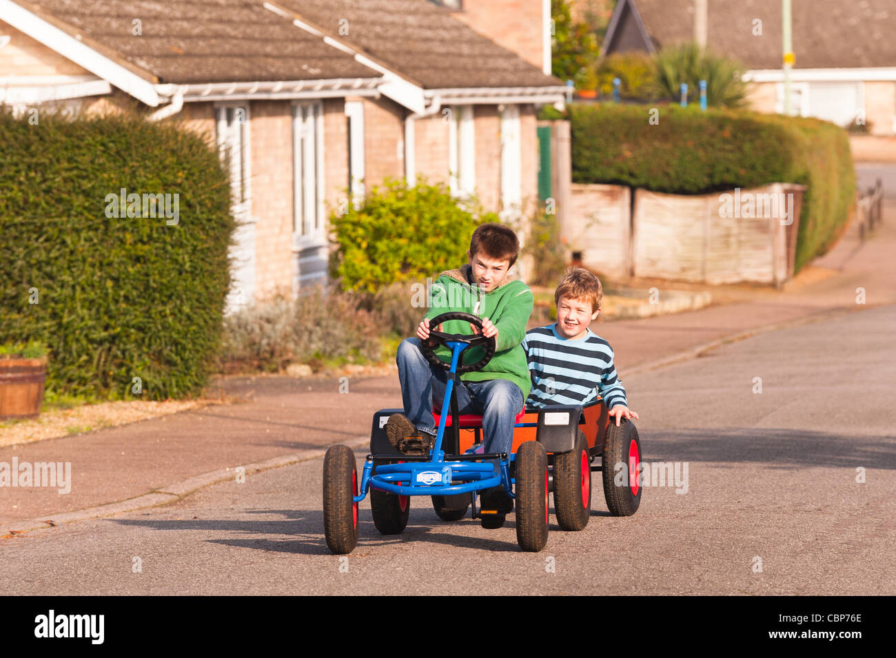 Due ragazzi giocare su un Berg go cart con il rimorchio in una strada del Regno Unito Foto Stock