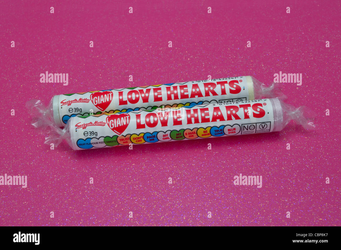 Due tubi di amore i Cuori dolci caramelle su un glittery sfondo rosa Foto Stock