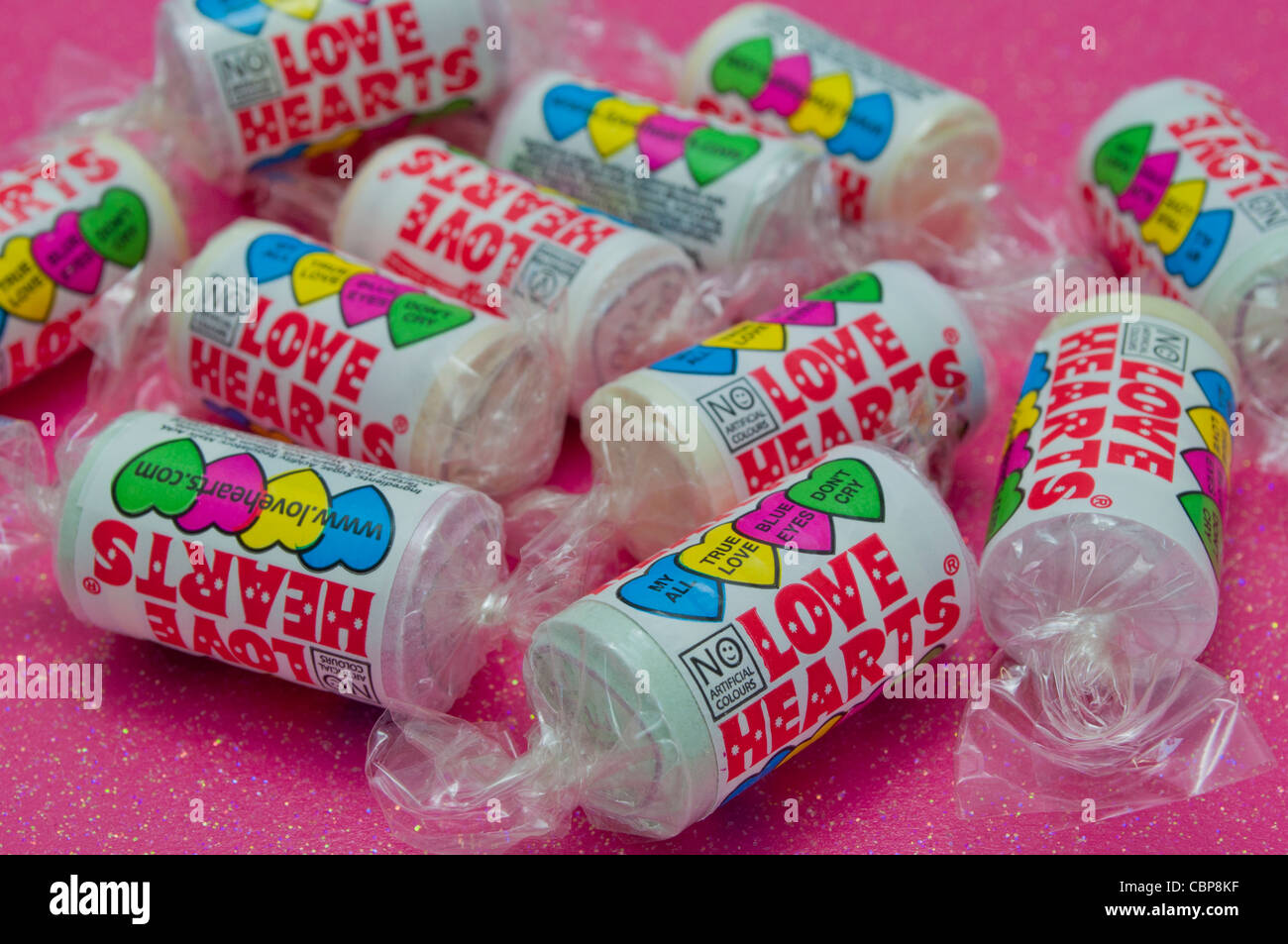 Tubi di amore i Cuori dolci caramelle su un glittery sfondo rosa Foto Stock