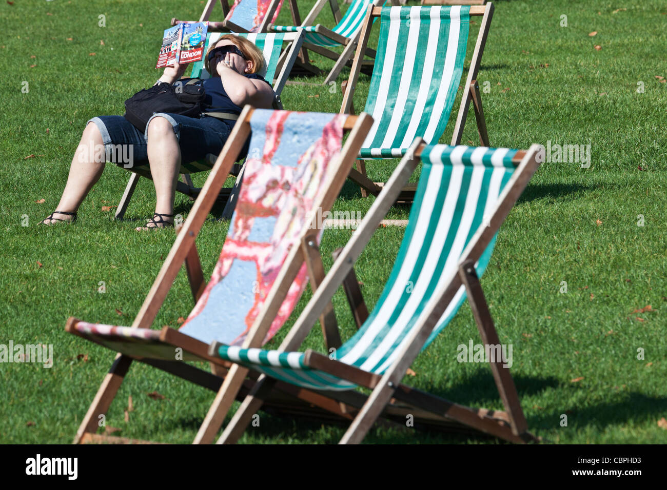Donna libro lettura in sedia a sdraio St James Park London Inghilterra England Foto Stock