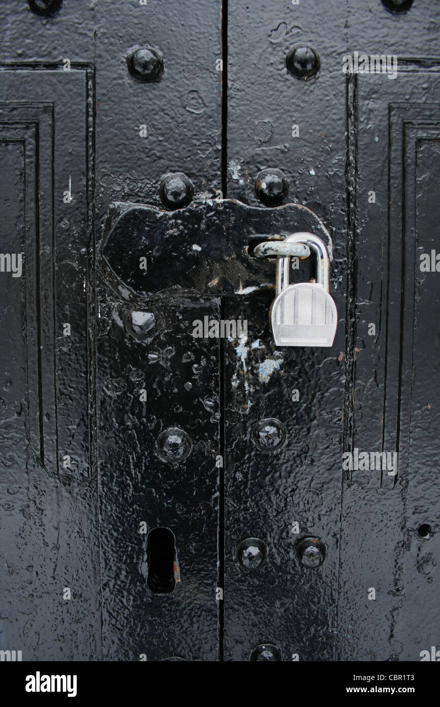 L'immagine verticale della cerniera a occhiello chiuso con lucchetto su nero dipinto di doppie porte Foto Stock