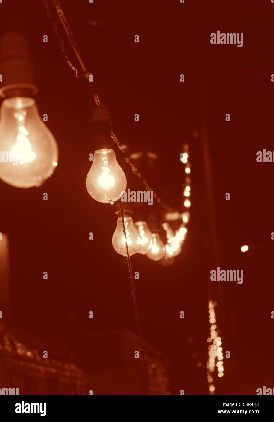 Una linea di lampade pendenti da un lampione post in India durante il festival. Le lampadine sono in umido con gocce di pioggia in corrispondenza della sua punta. Foto Stock