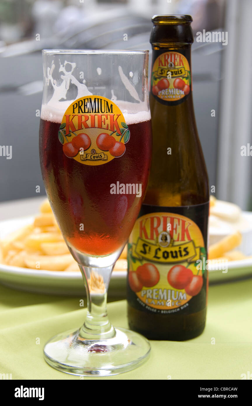 Verticale fino in prossimità di un frutto tradizionale Lambic birra belga bottiglia di vetro e davanti ad un piatto di patatine fritte e mayo. Foto Stock