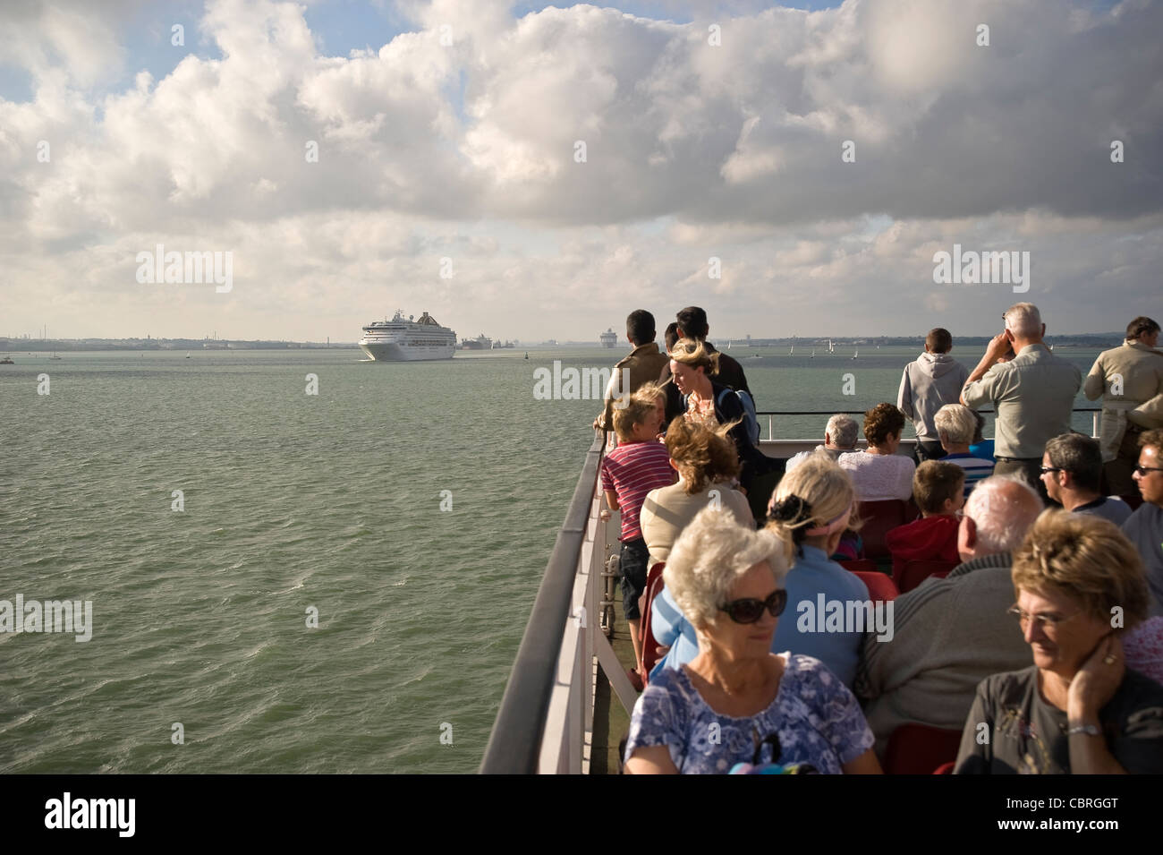 I passeggeri su un isola di Wight traghetto per auto la visione di una grande nave da crociera passano sul Solent vicino a Southampton, Regno Unito Foto Stock