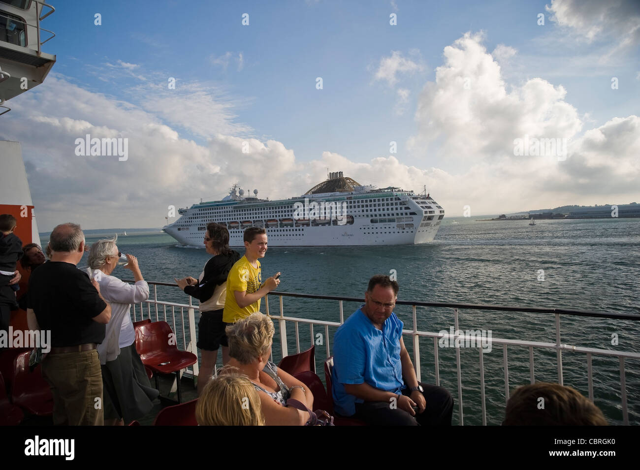 I passeggeri su un isola di Wight traghetto per auto la visione di una grande nave da crociera passano sul Solent vicino a Southampton, Regno Unito Foto Stock