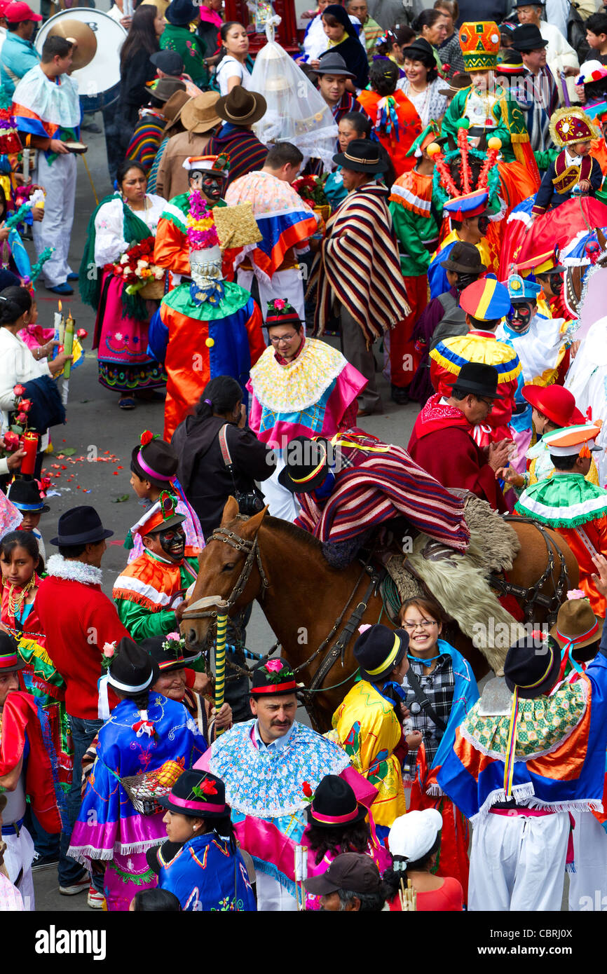 Una folla vivace e densamente affollata in un festival tradizionale, con persone in costumi e cappelli elaborati e colorati. Molti indossano poncho, maschere e copricapi con motivi e piume brillanti. A. Foto Stock