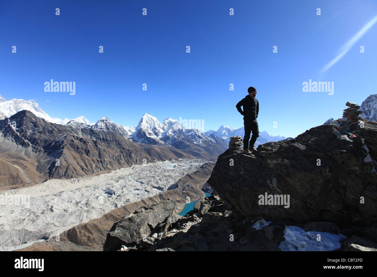 L uomo sta sul Vertice di Gokyo-Ri. Vista del villaggio di Gokyo, ghiacciaio della valle e il lago in Himalaya Foto Stock