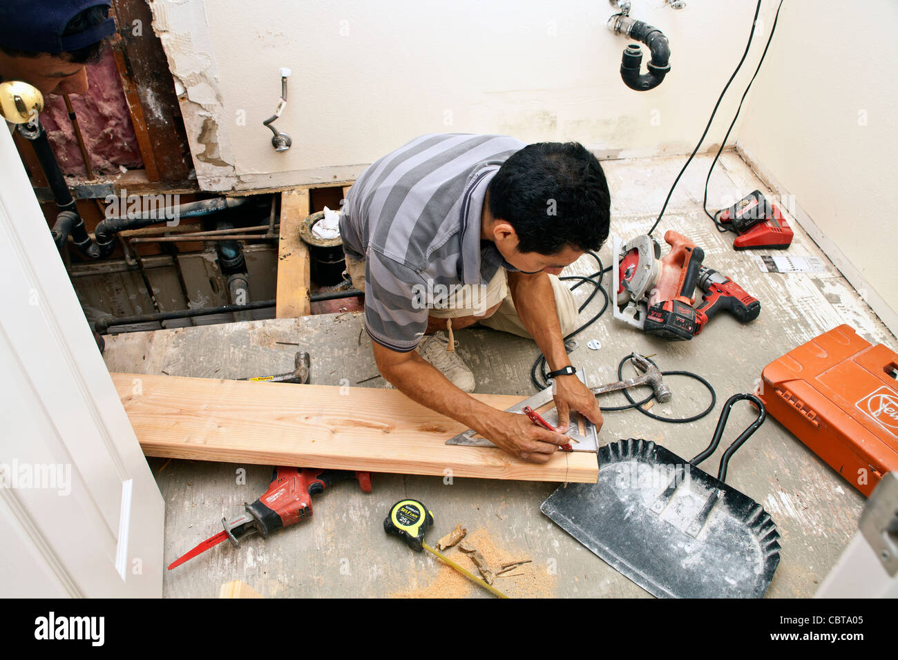 Uomo ispanico dal Messico il suo lavoro di costruzione propria azienda negli Stati Uniti sostituisce la trave di supporto nel bagno al piano di sopra USA. Signor © Foto Stock